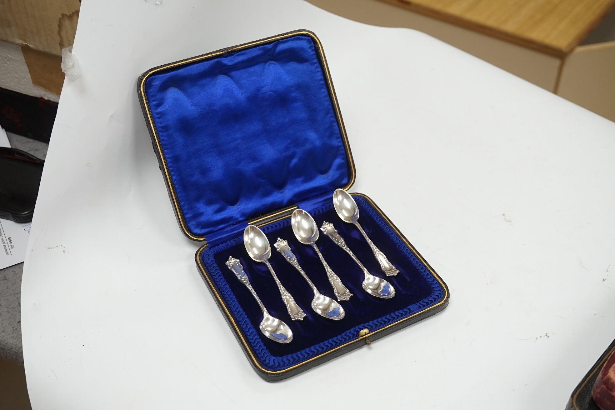 A cased set of six George V silver teaspoons, two cased sets of six silver handled tea knives, fourteen assorted items of 19th century and later silver spoons and a pair of silver sugar tongs. Condition - fair to good